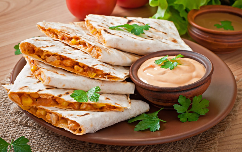 mexican quesadilla sliced with vegetables sauces table