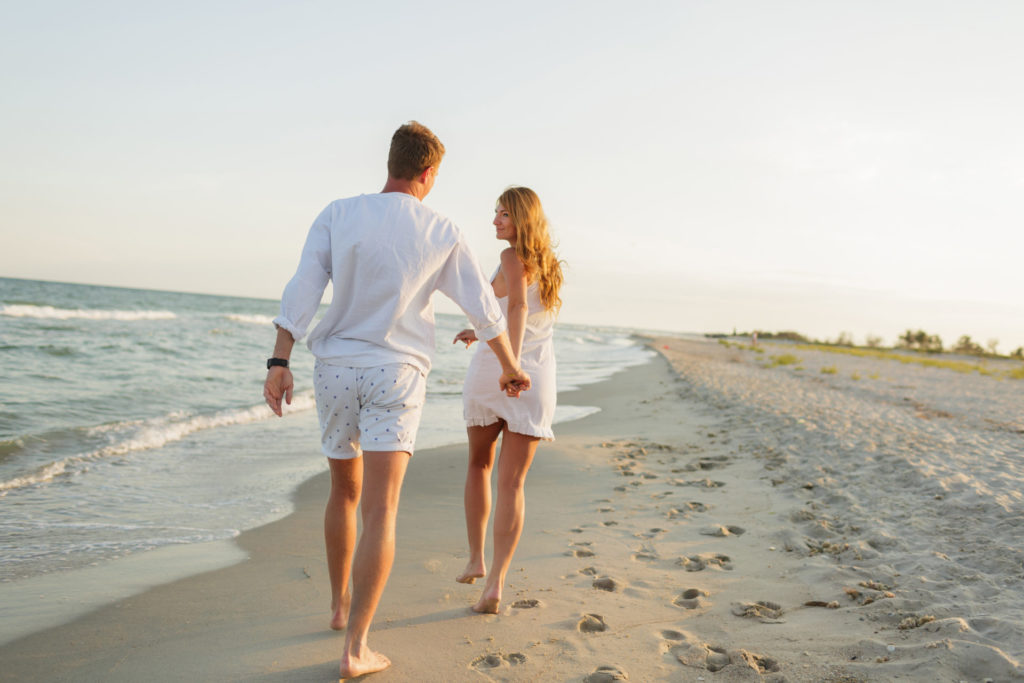 young beautiful couple walks along the seashore at sunset